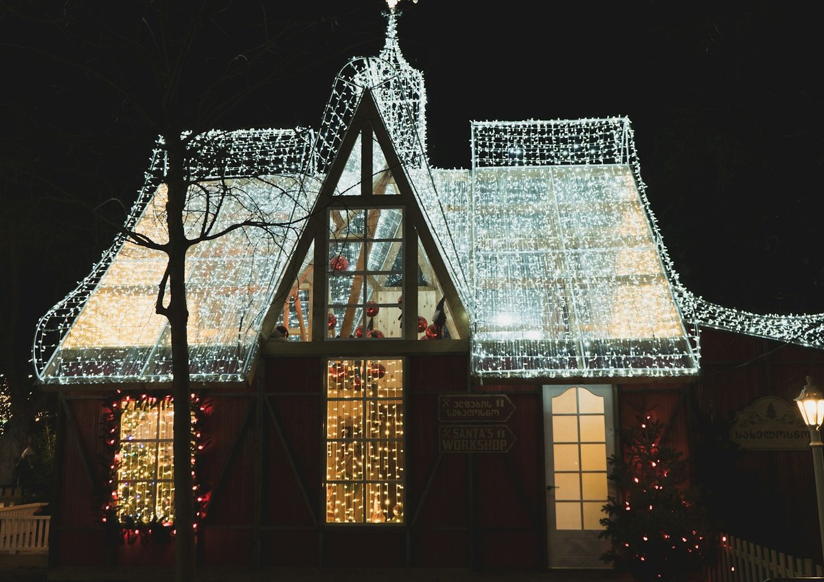 Warm white icicle lights hanging from a snow-covered house roof