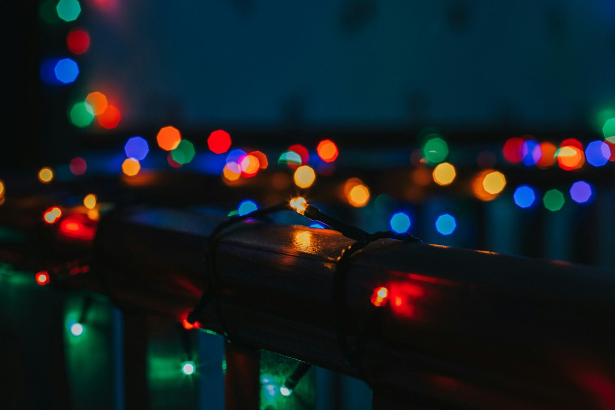 Colorful string lights wrapped around a wooden railing at night